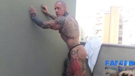 The legend of muscles and ink: Tattooed giant Rob Diesel, shows his power on the balcony